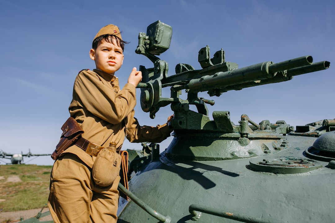 a boy in a uniform standing next to a tank