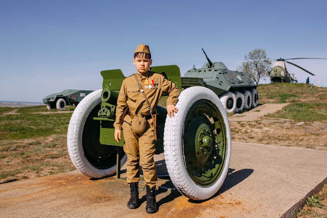 a boy in uniform standing next to a large tire